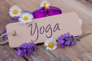 yoga written on a card with purple flowers and candle